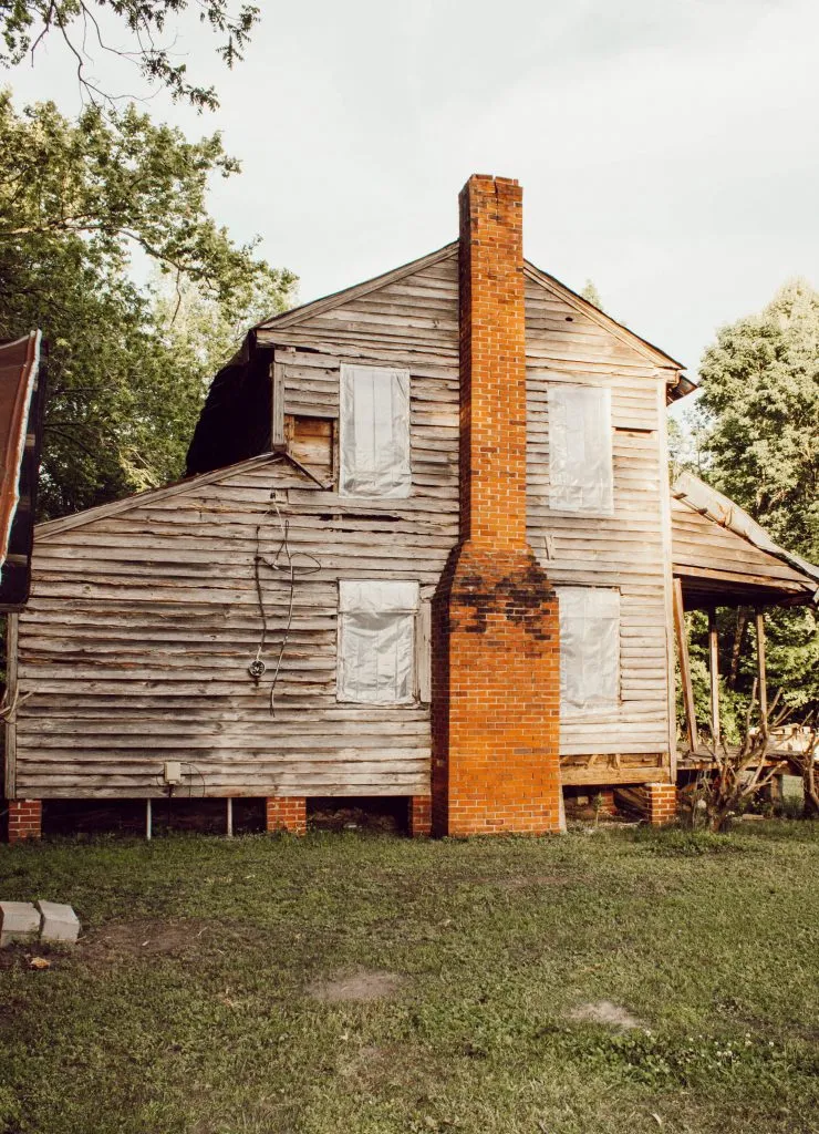 1800's nc farmhouse exterior with weathered wood siding and red brick chimney