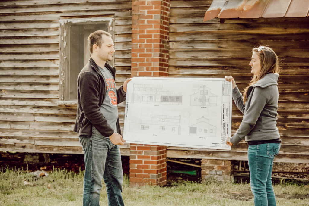 couple holding blueprints for 1800's NC farmhouse fixer upper