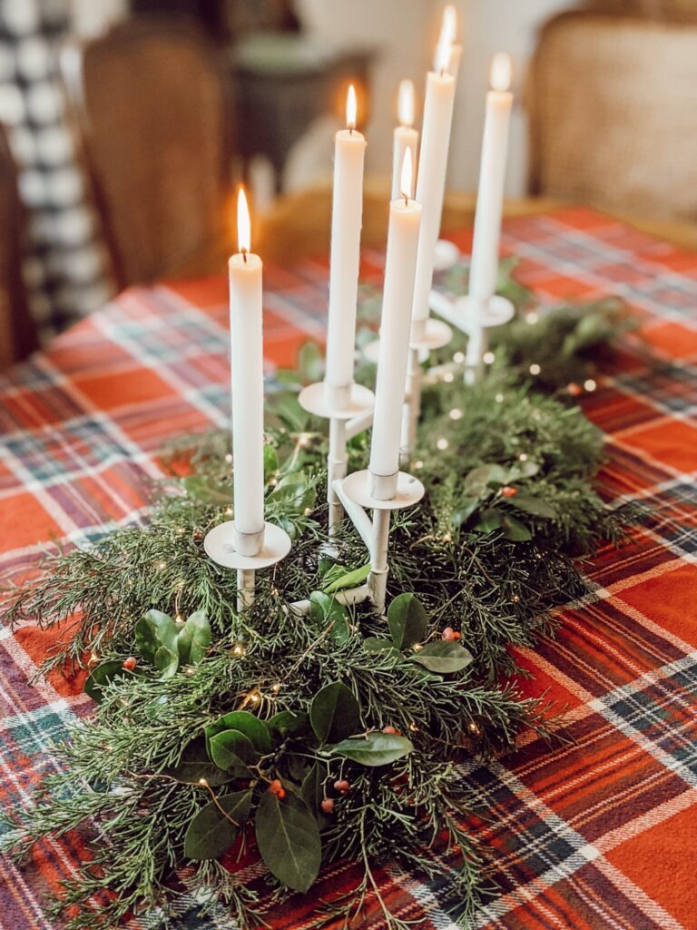 holiday centerpiece with tapered white candles and fresh greenery 