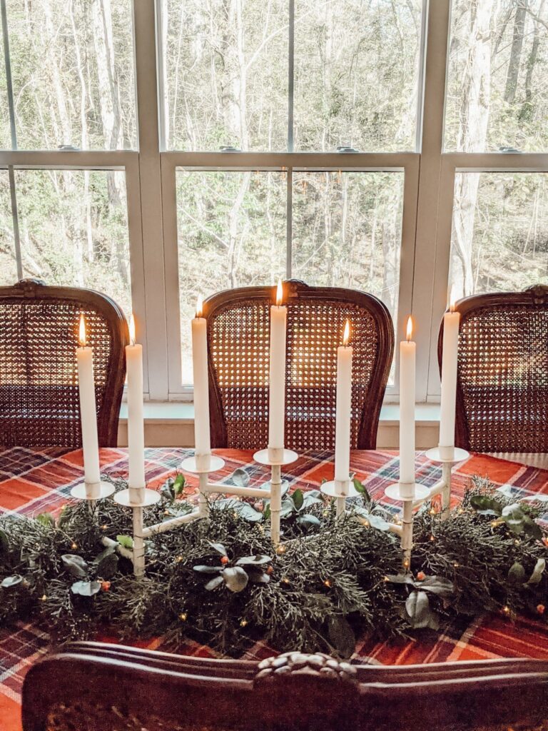 christmas tablescape with fresh greenery and candles, and cane back dining chairs