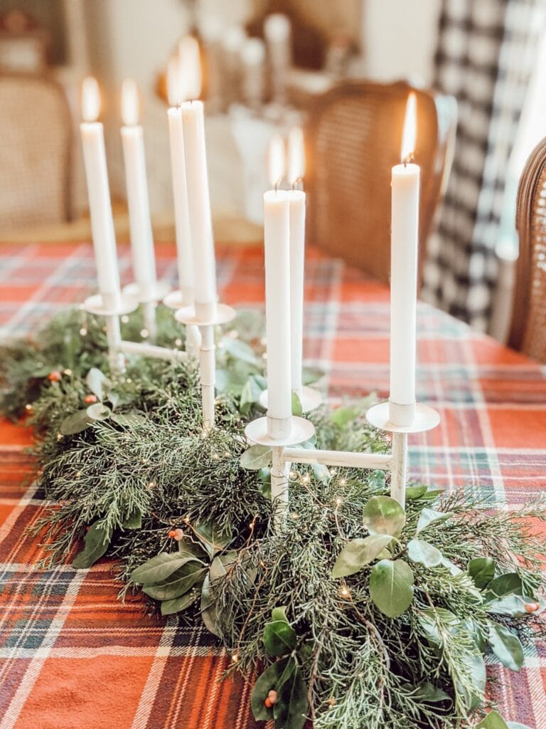 christmas tablescape with red plaid tablecloth, candles, and fresh greenery