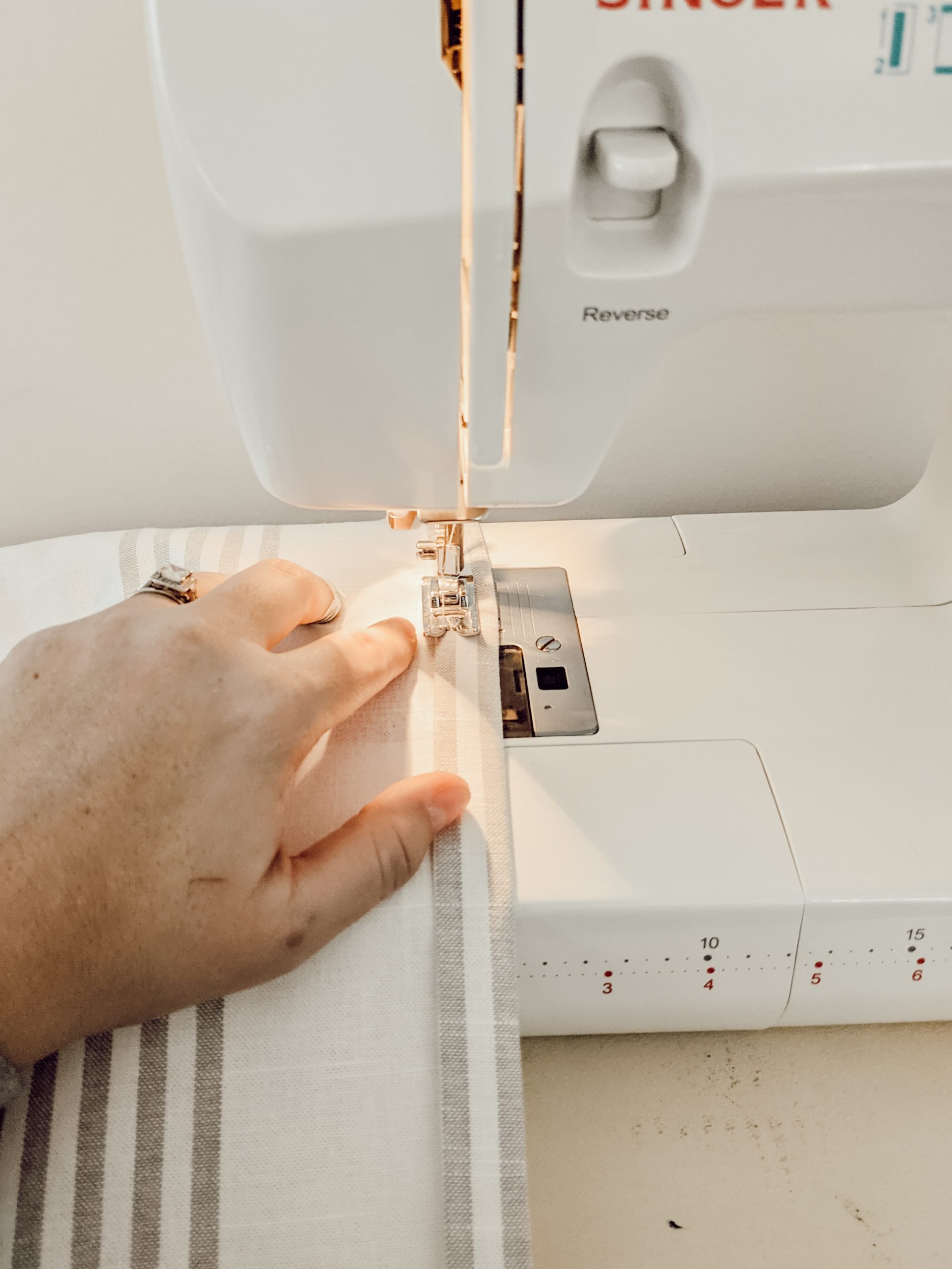 sewing the hem of a curtain on a white sewing machine