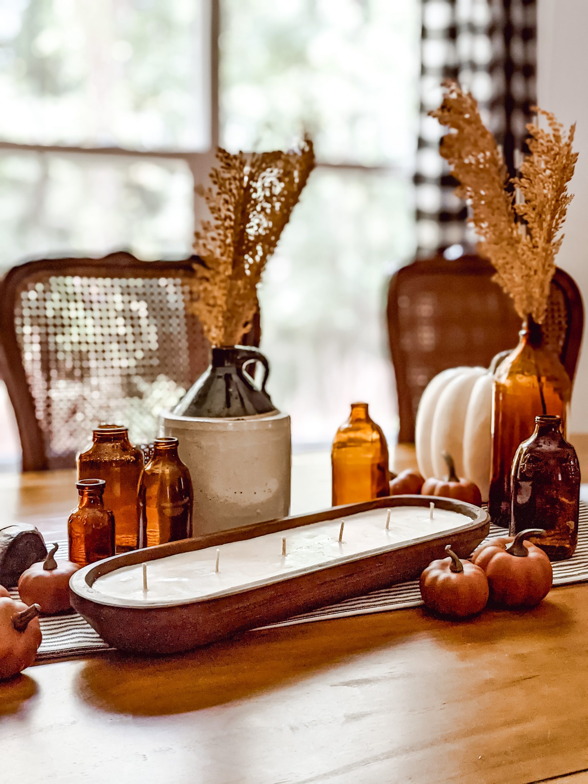 farmhouse tablescape with amber glass, pumpkins, and a dough bowl candle