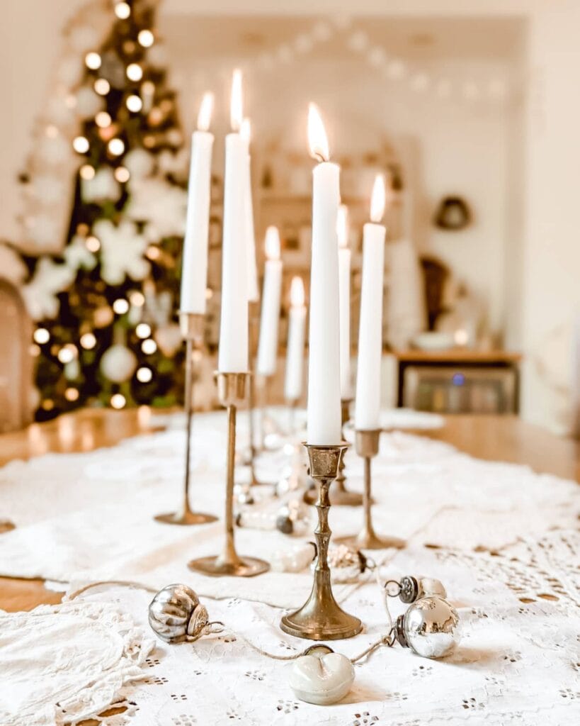 brass candlesticks, doilies, and mercury glass ornament in neutral christmas tablescape
