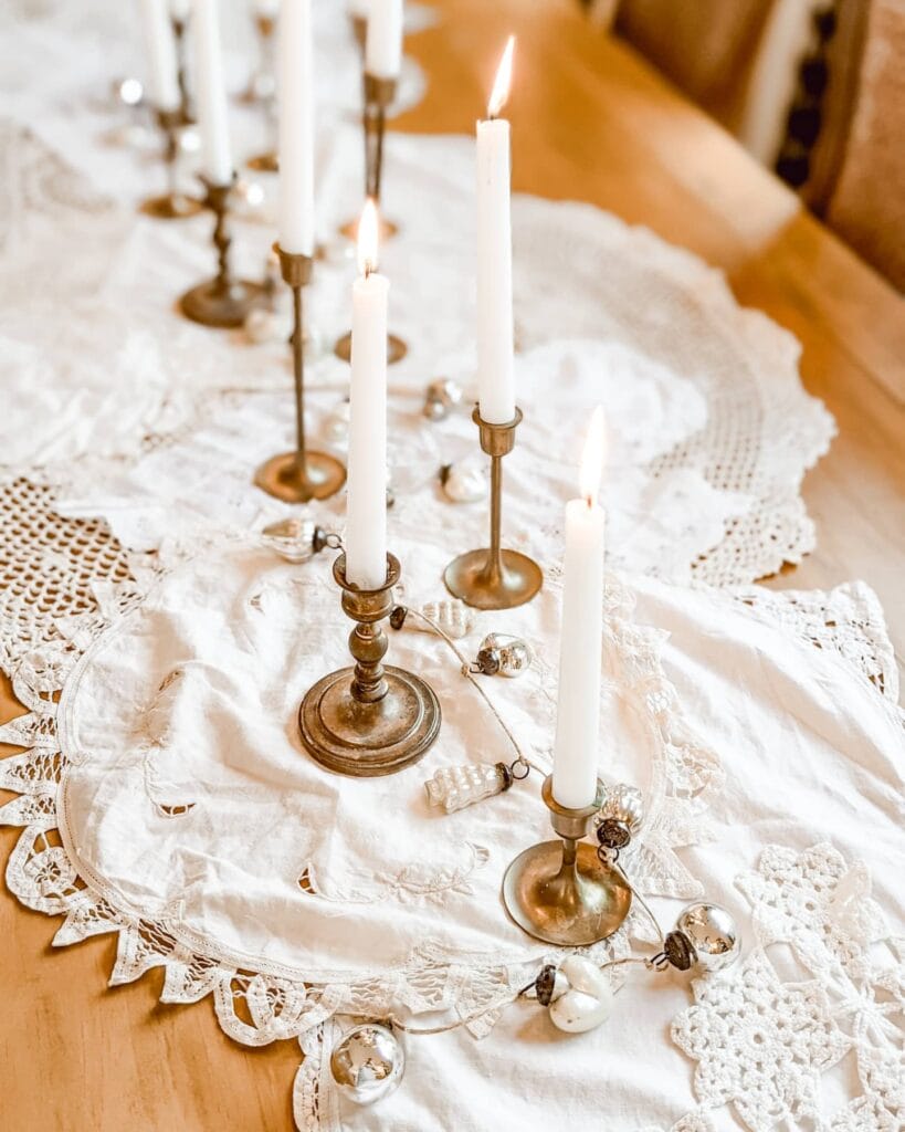 vintage lace and crochet doilies layered on table as a vintage table runner with brass candlesticks