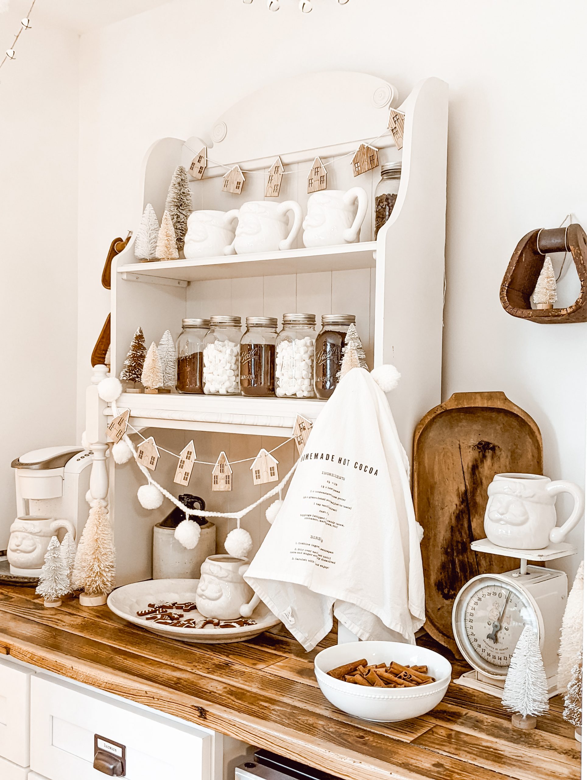 neutral Christmas cocoa bar with white Santa mugs and vintage wood decor