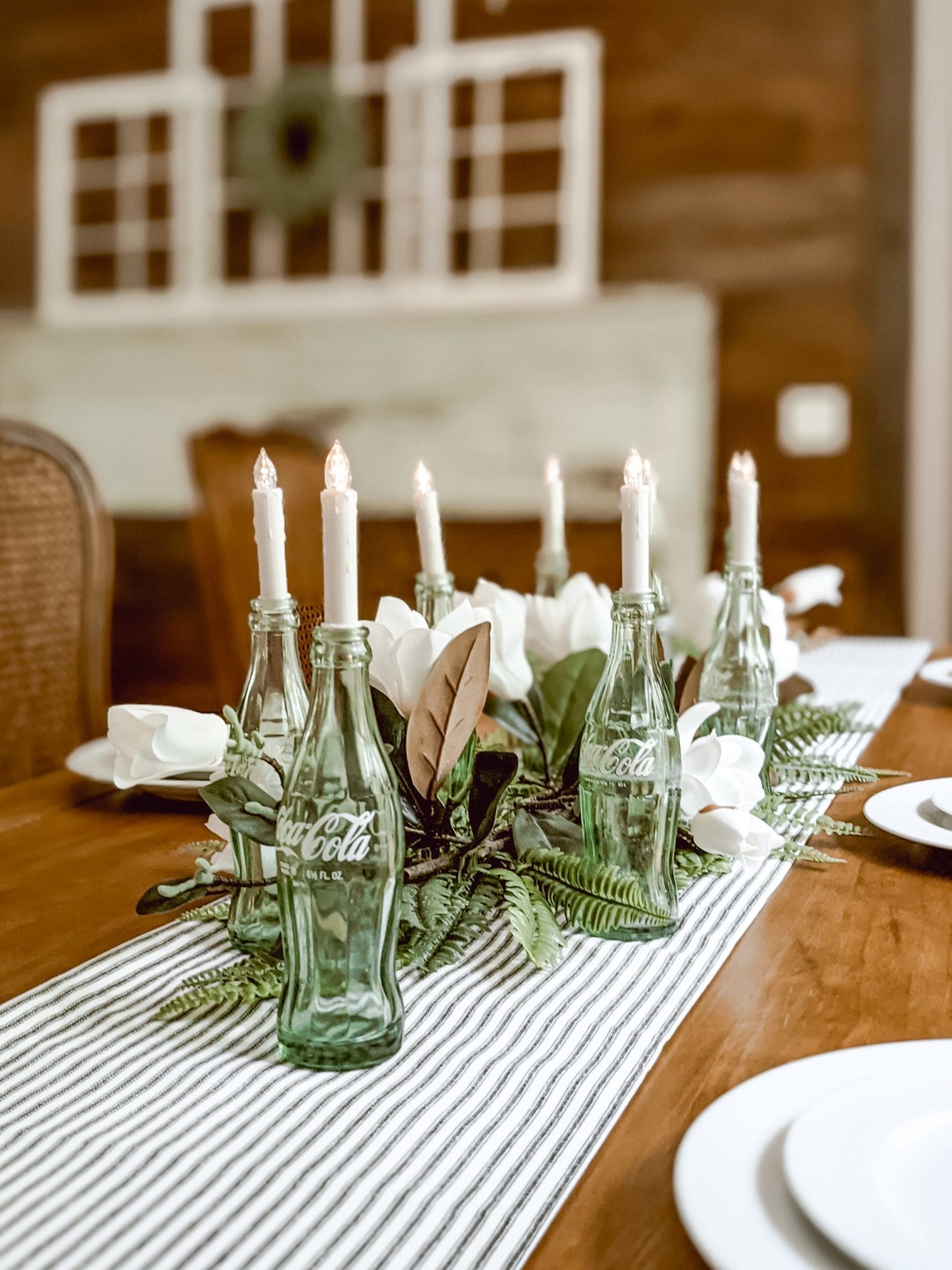 reuse green glass coca cola bottles as tapered candle holders for a table centerpiece