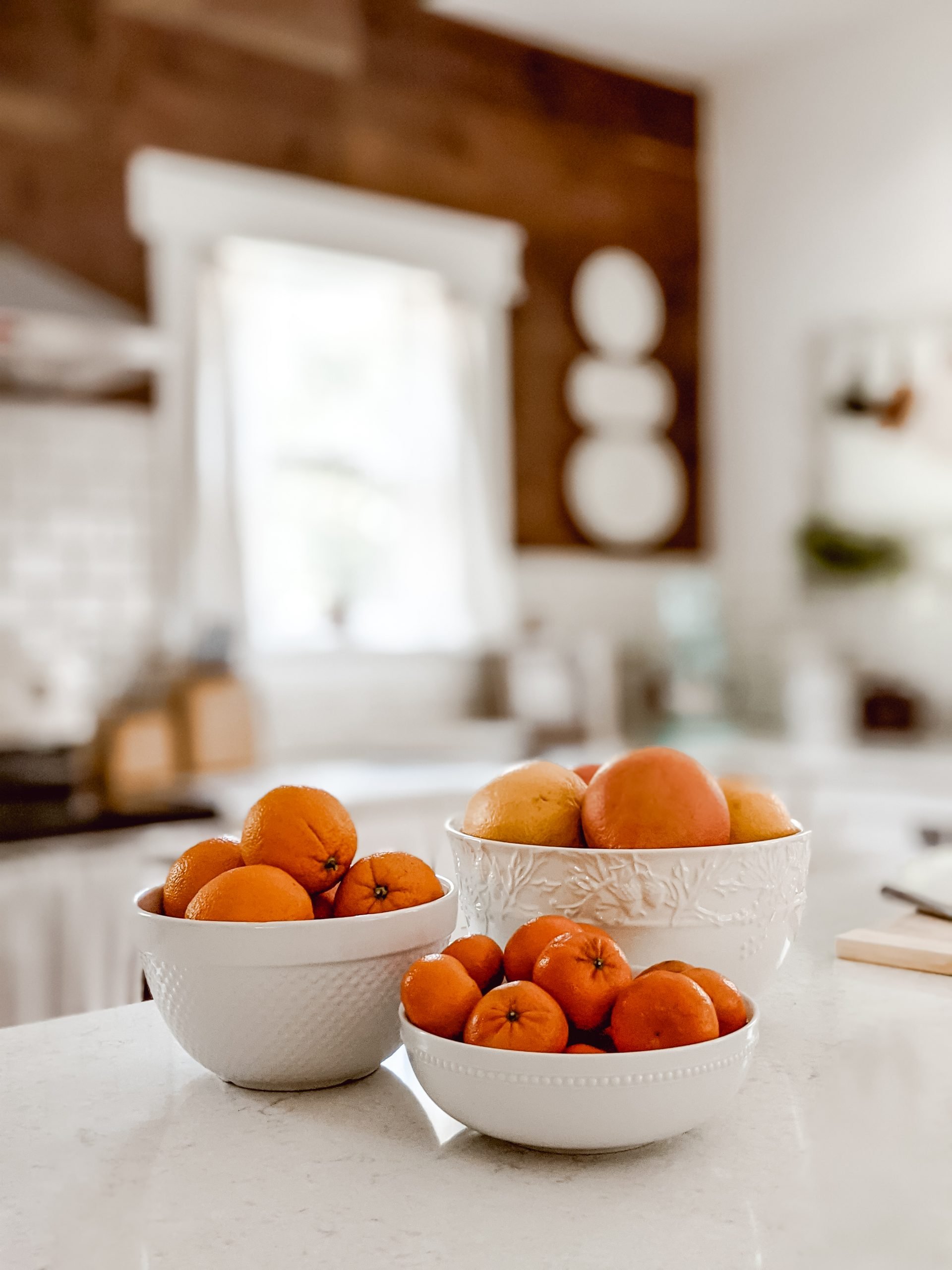 white bowls of oranges, grapefruit, and clementines