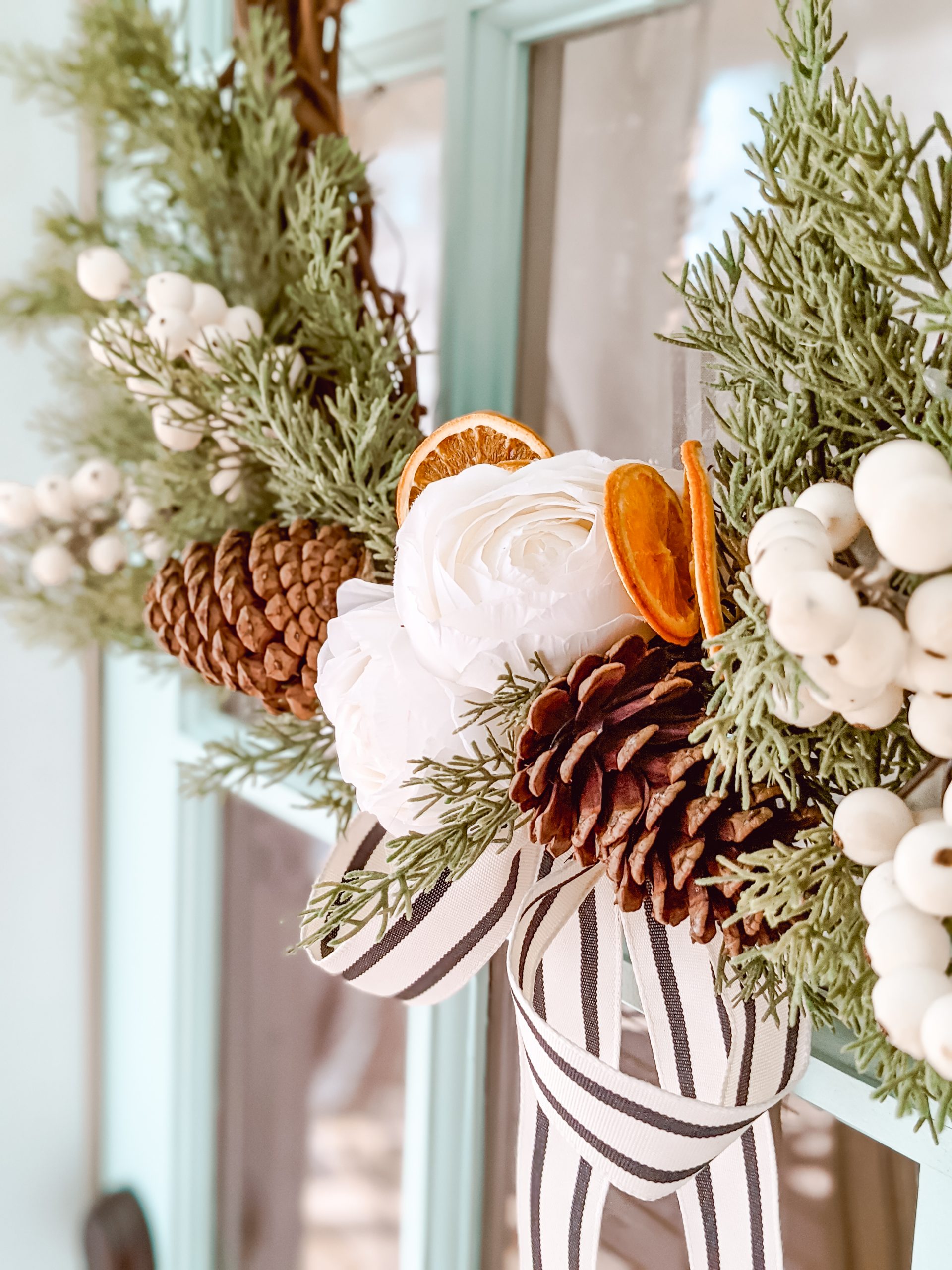 classic grapevine wreath with faux cedar, pine cones, white florals and dried oranges