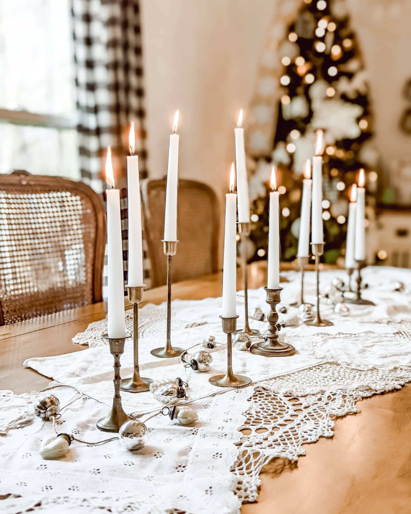 cottage Christmas tablescape with vintage doilies, brass candlesticks, and a mercury glass ornament garland