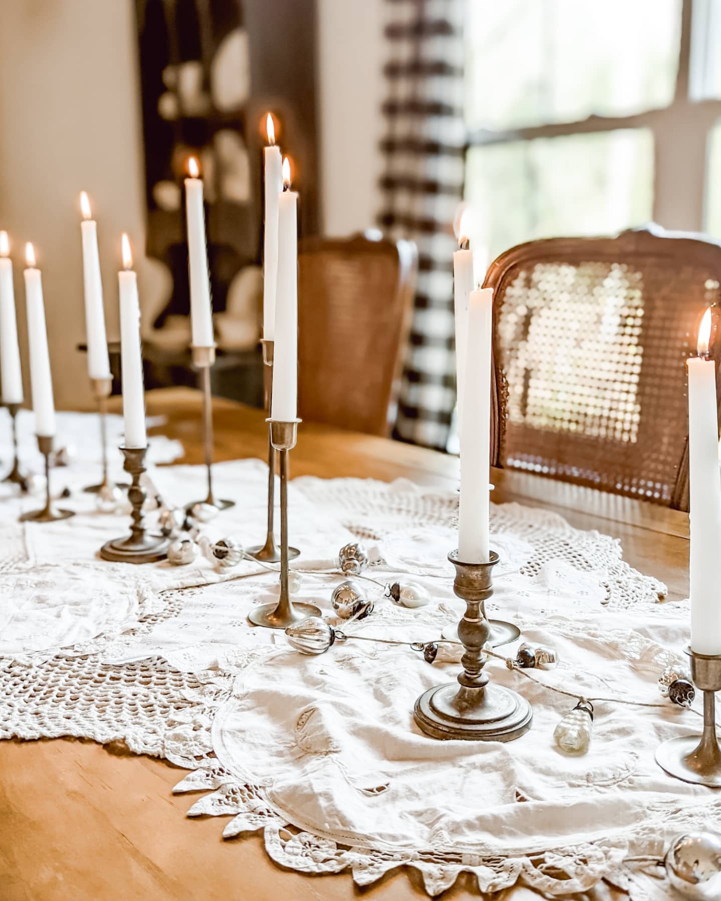 vintage Christmas tablescape with old doilies, brass candlesticks, and a mercury glass ornament garland