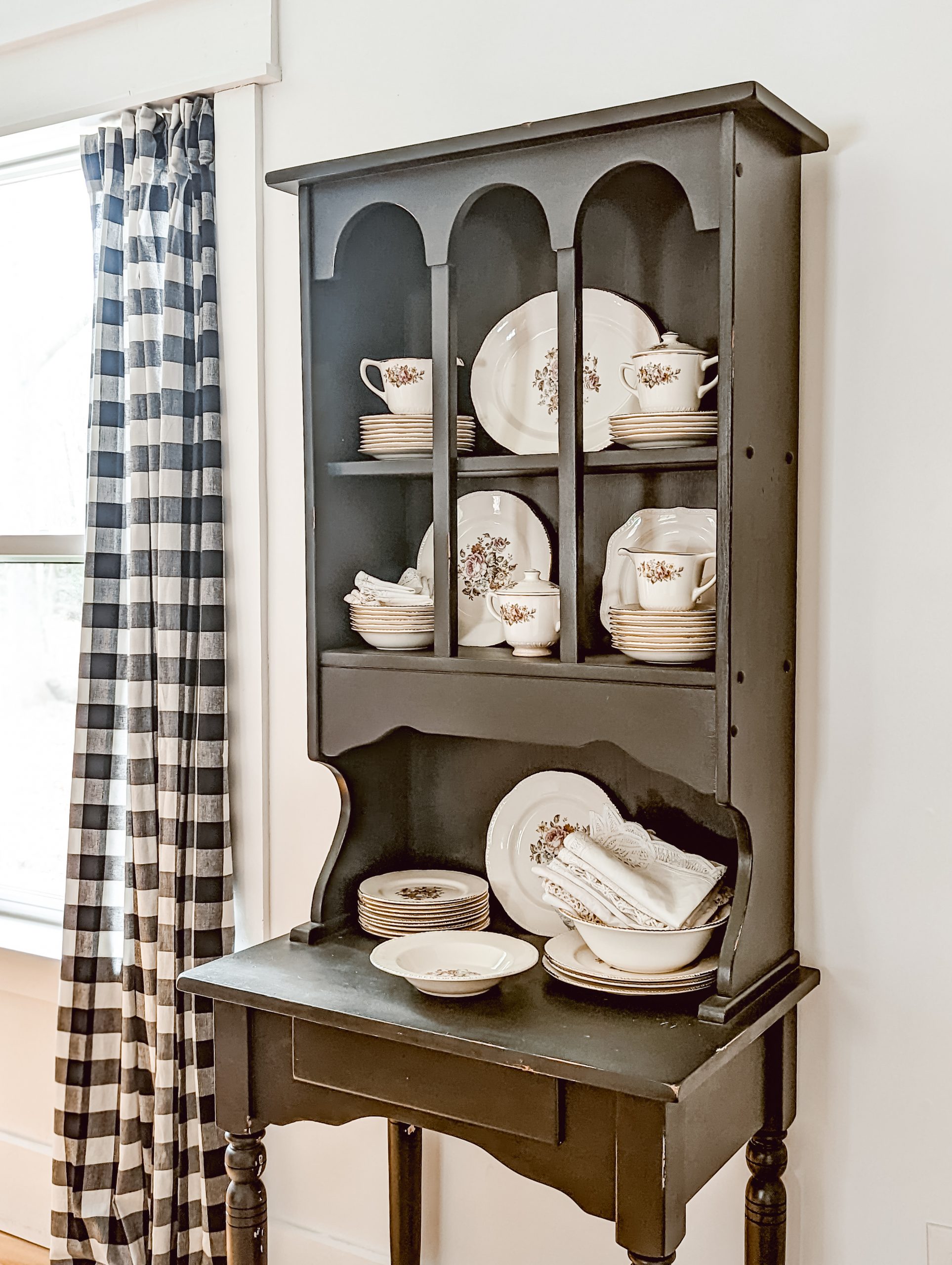 black arched hutch with open shelves for displaying china