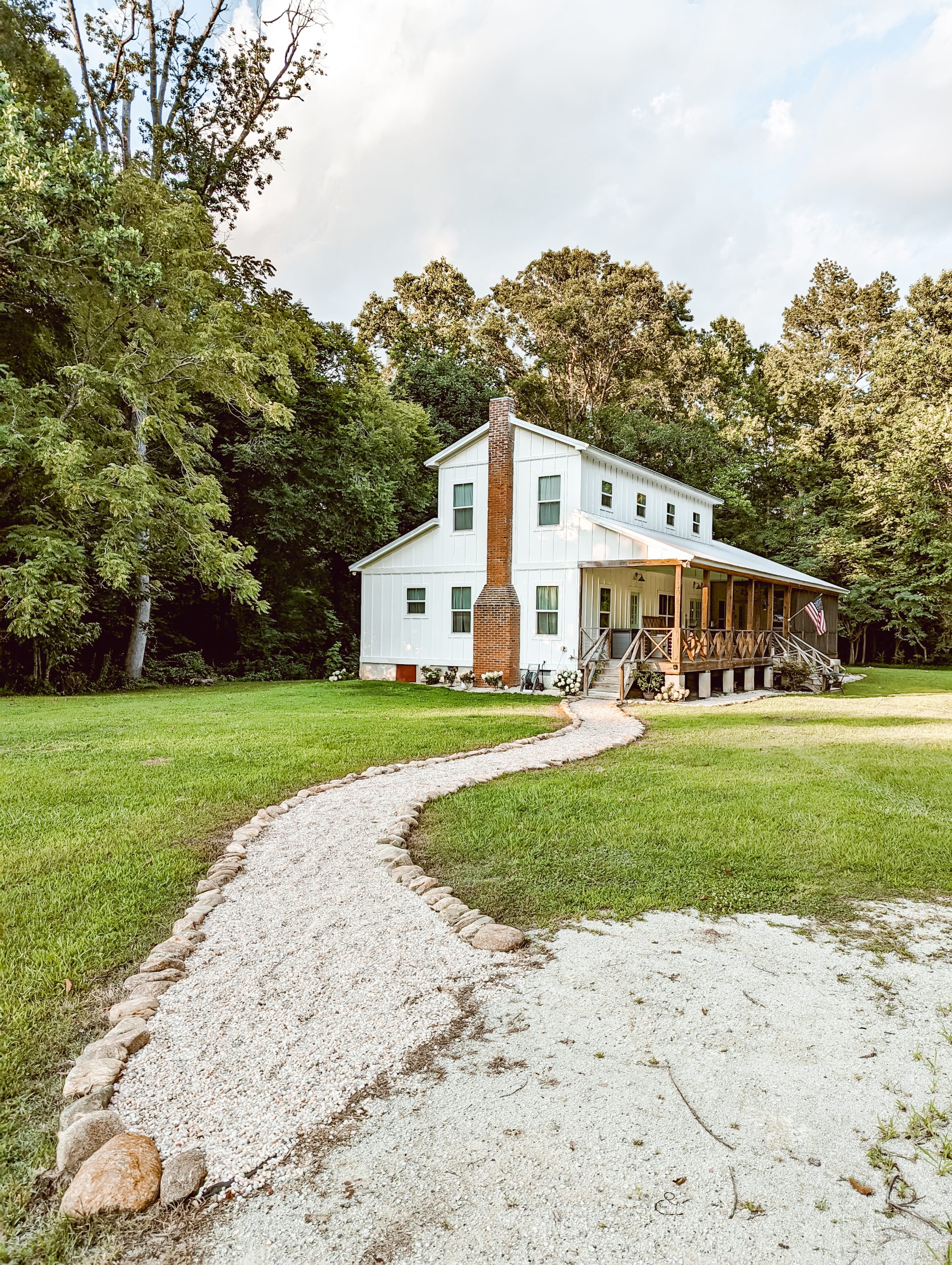 white farmhouse exterior with simple country landscaping and a pea gravel walkway leading to the front porch