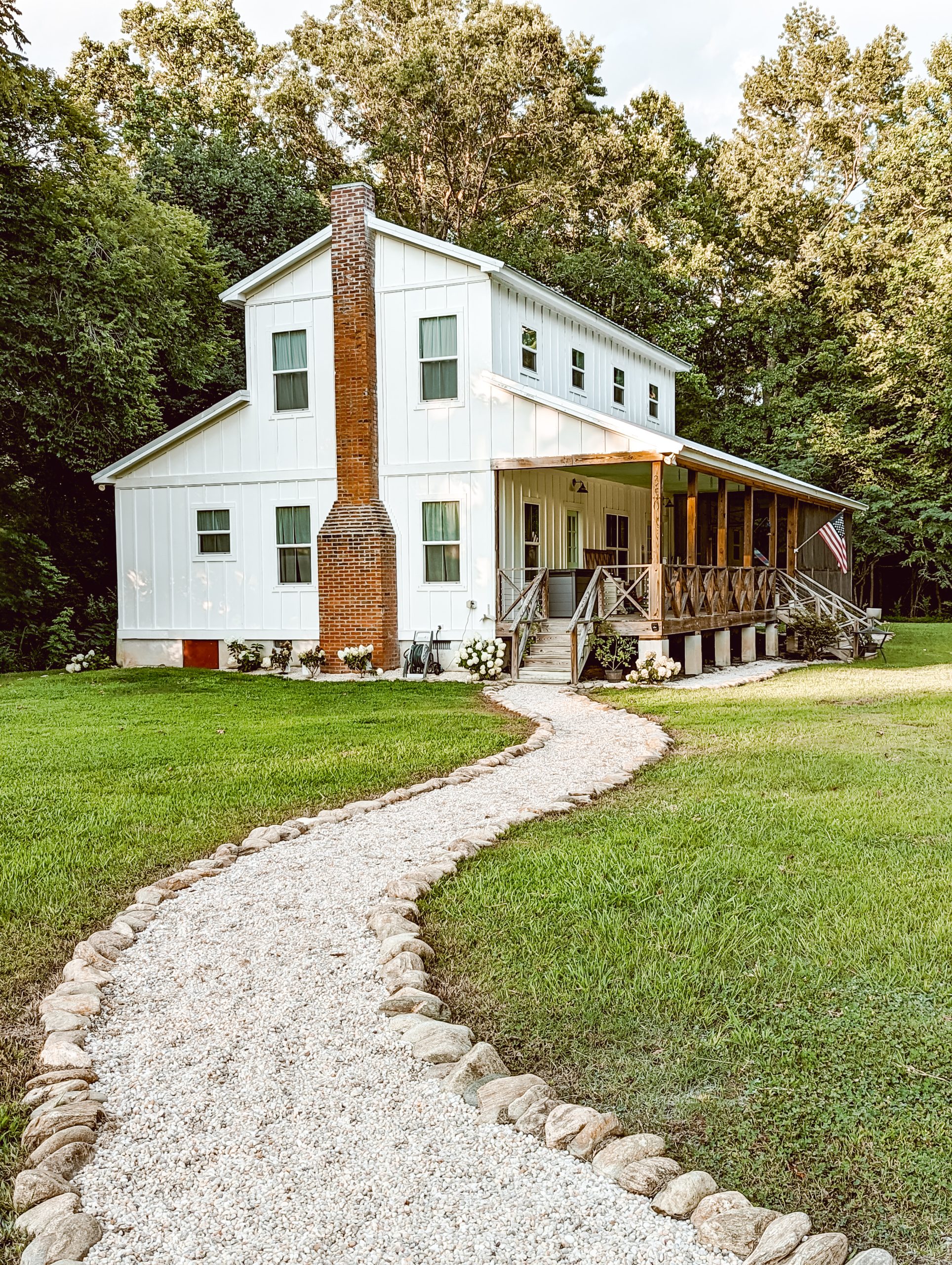 country white farmhouse exterior landscaping with a DIY gravel path leading up to the porch steps