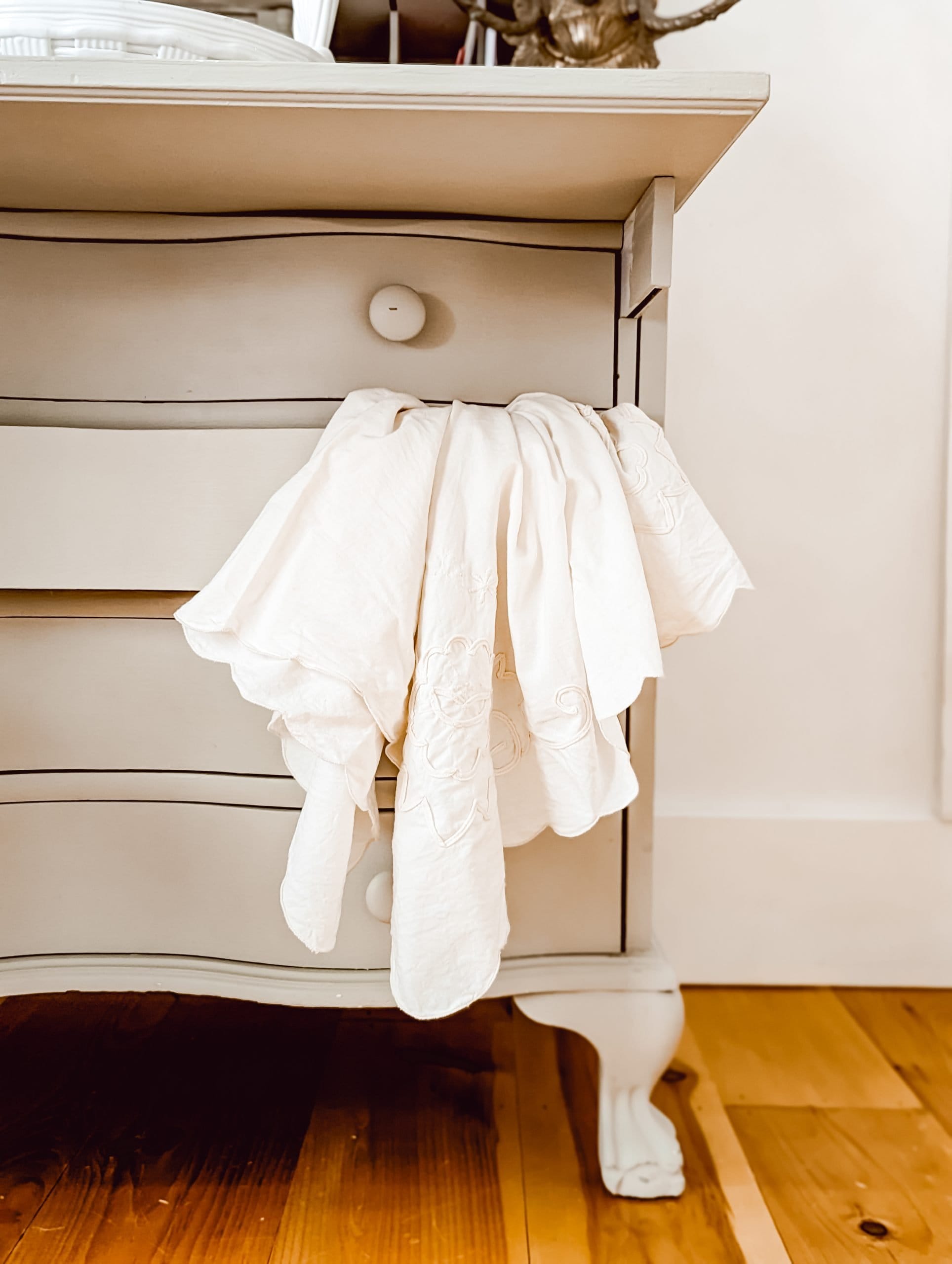 white embroidered table linen tucked into a dresser drawer 