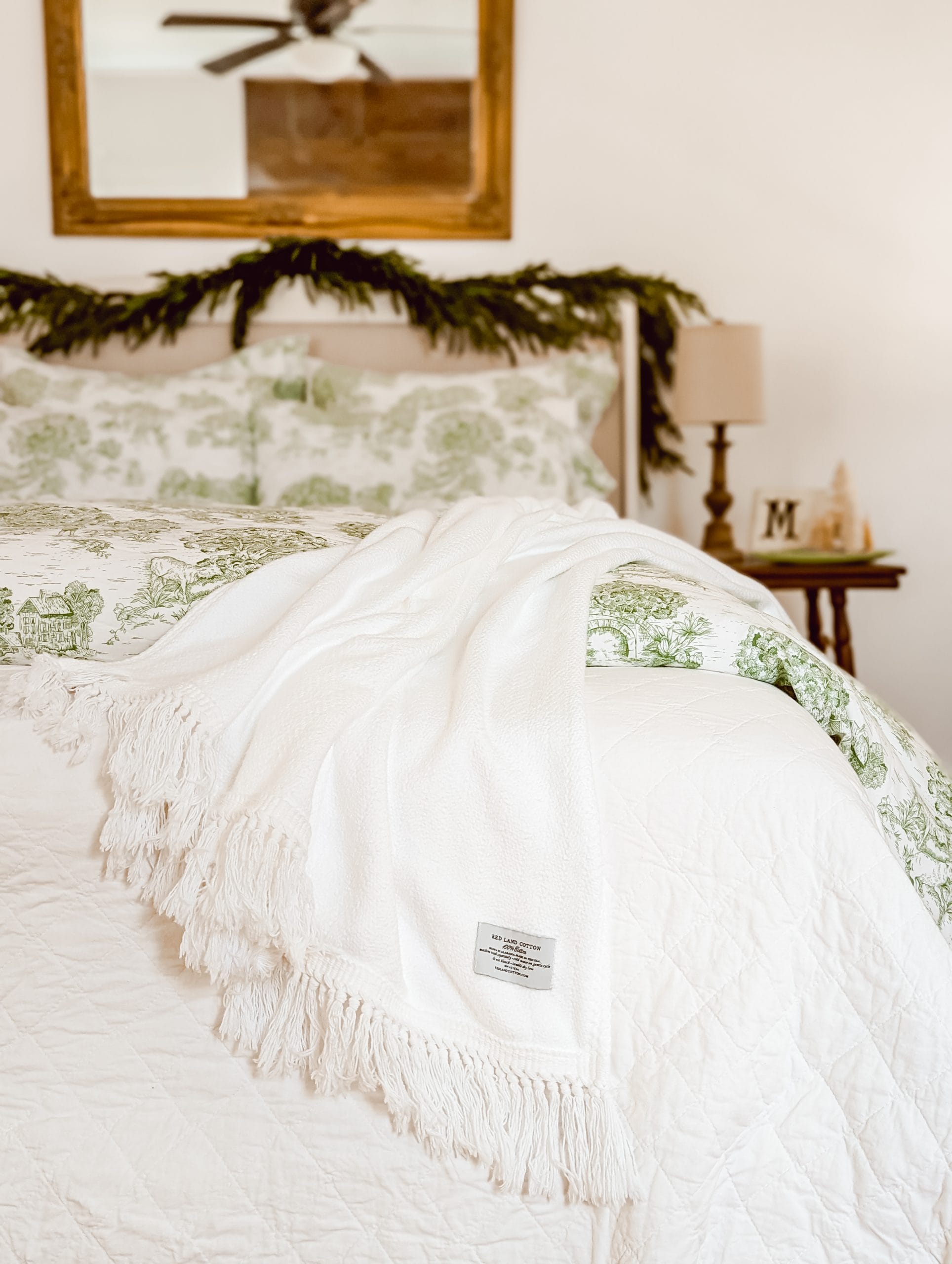 layers of green toile and white bedding from Red Land Cotton styled in a french country farmhouse bedroom for Christmas
